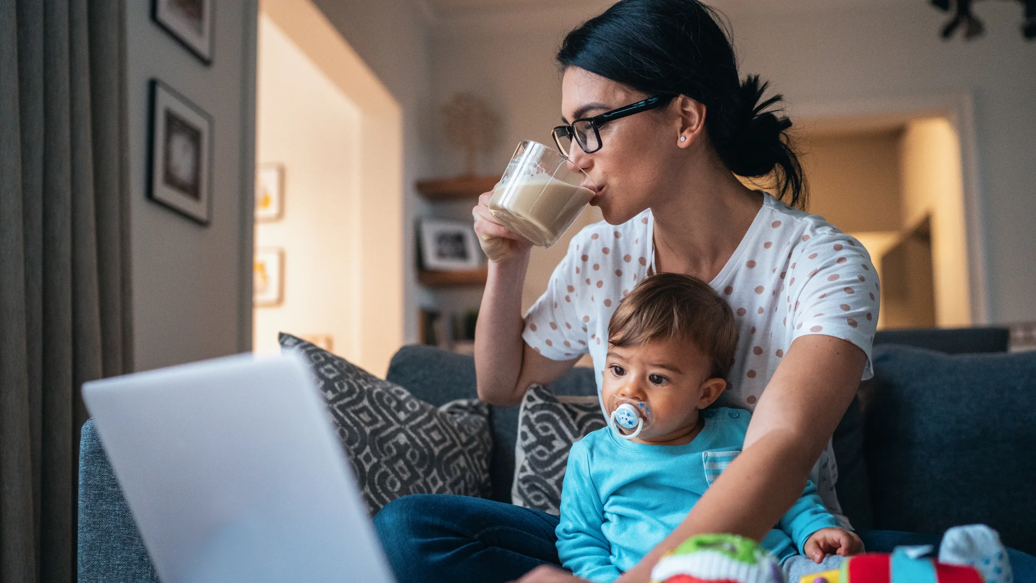 A woman and her baby enjoy milk together while sitting comfortably on a couch.