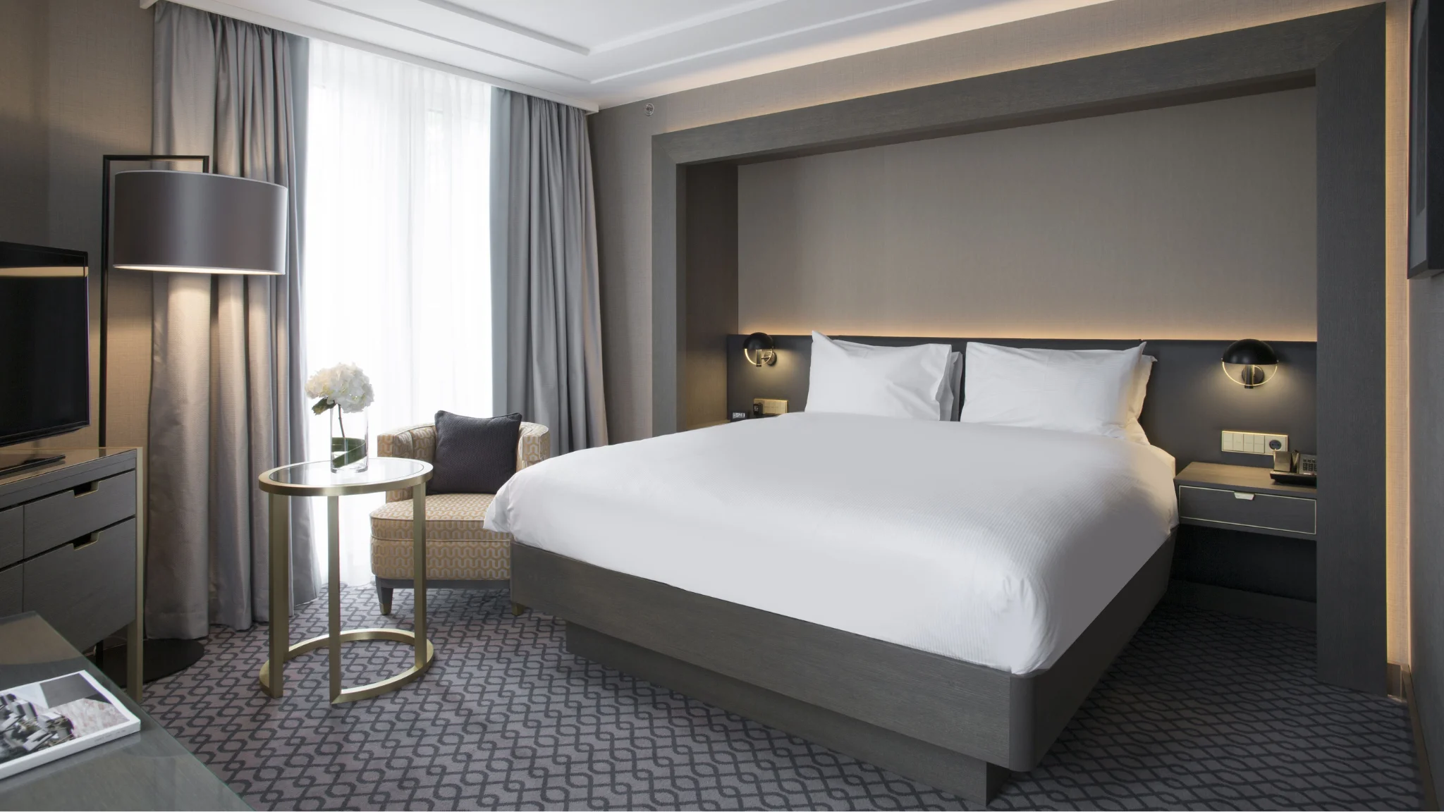 A cozy hotel room featuring a bed, desk, and television, perfect for relaxation and work.
