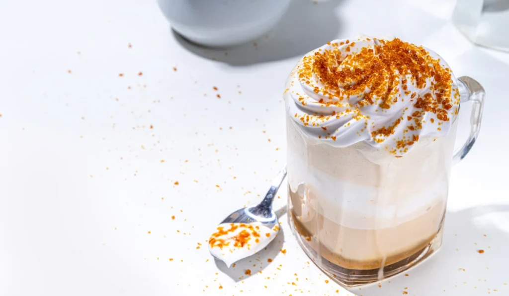 On a white table, a drink and a spoon are placed, suggesting a cozy moment.