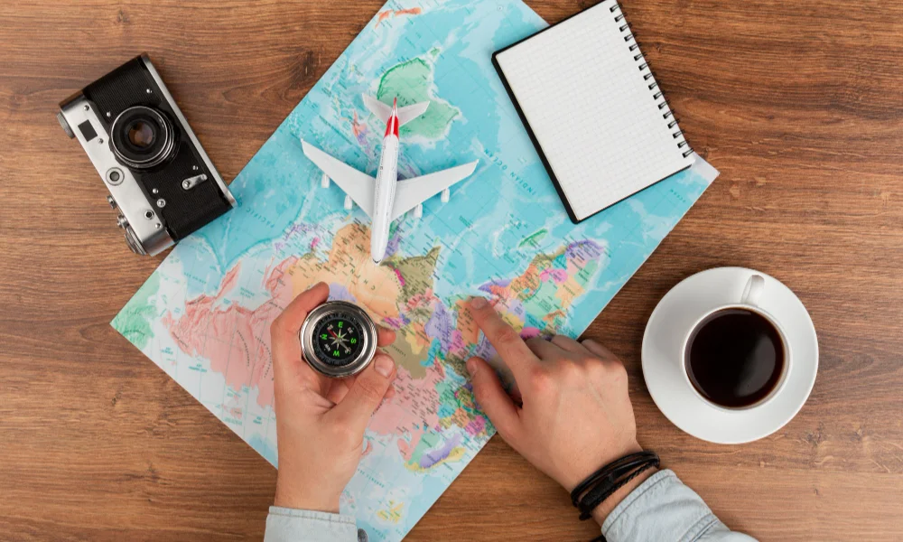 person points to a world map on a wooden table-international travel tips