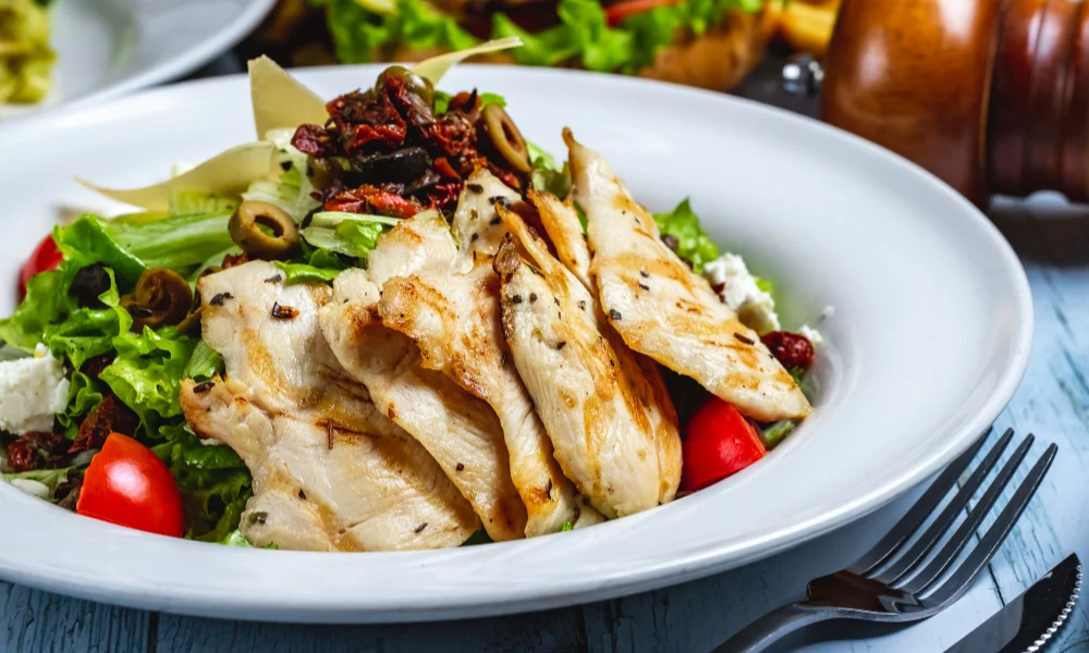 A white plate with a grilled chicken salad