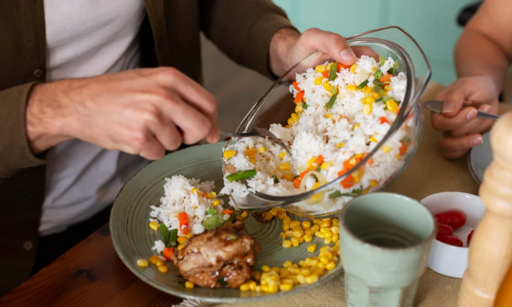 A person is serving colorful vegetable rice