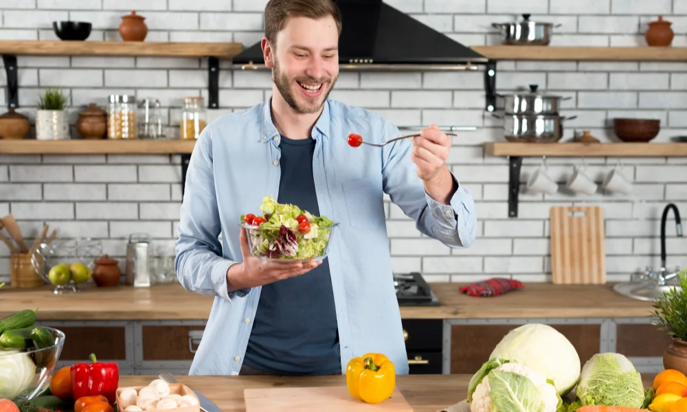 A smiling man in a kitchen holds a salad bowl-Sexy Healthy Cooking