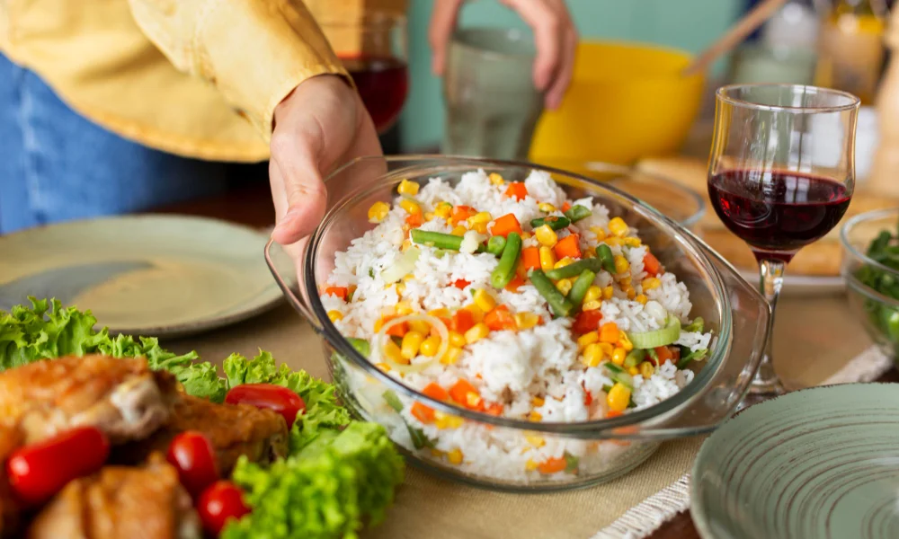 A person serves a bowl of colorful rice