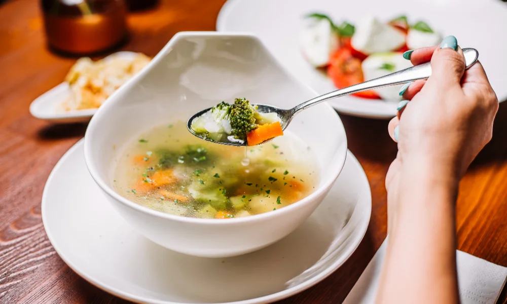 A person holding a spoonful of vegetable soup-slow cooker soup healthy