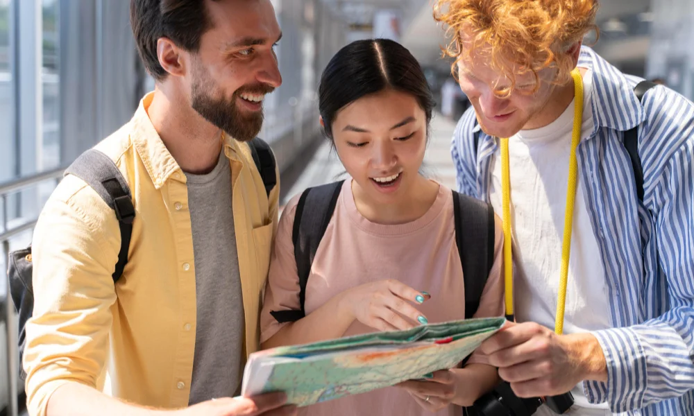Three young adults eagerly examining a map-international travel tips