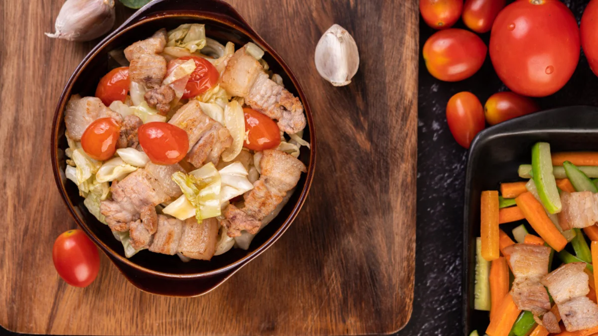 A bowl of stir-fried pork belly with cherry tomatoes