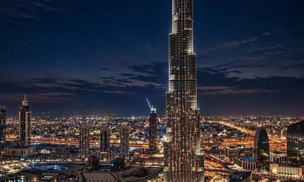5 must visit places in Dubai highlights the illuminated Burj Khalifa tower and the surrounding Dubai Fountain system against the night city skyline.