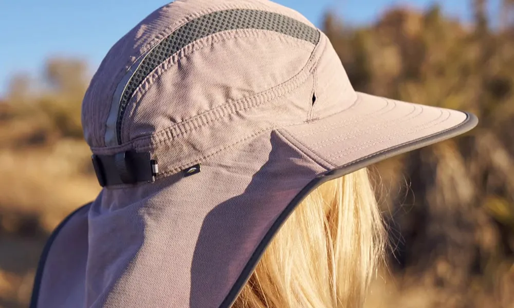 Best Hiking Hats featured in a light mauve full-coverage sun cap with a protective neck flap and ventilation stripe worn outdoors. 