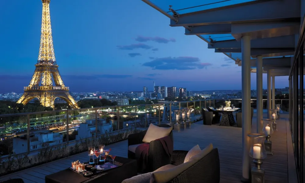 Luxury hotel terrace overlooking the illuminated Eiffel Tower for Best Hotels in Paris.
